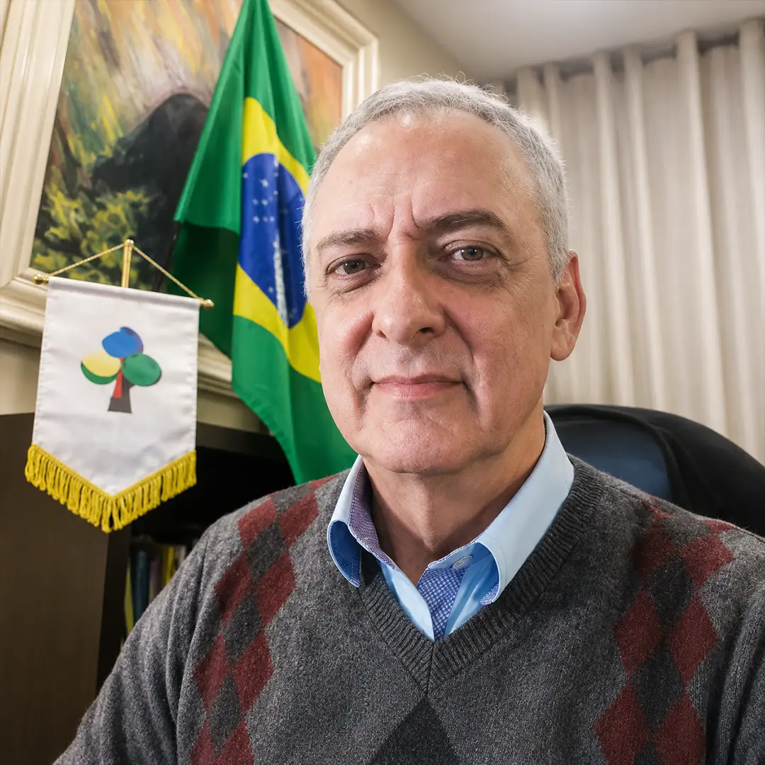 Thomas Korontai em retrato institucional com bandeira do Brasil ao fundo para página Sobre